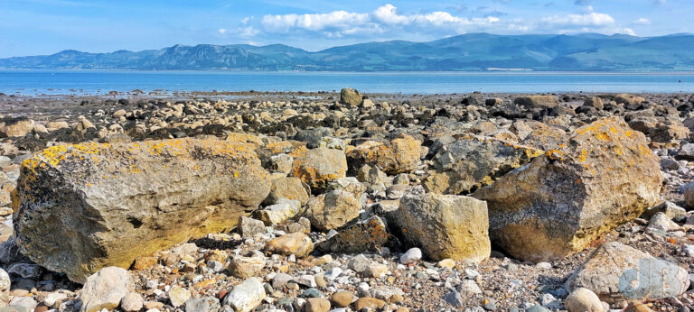 Snowdonia viewed beyond the rocky beach at Penmon and the Menai Strait