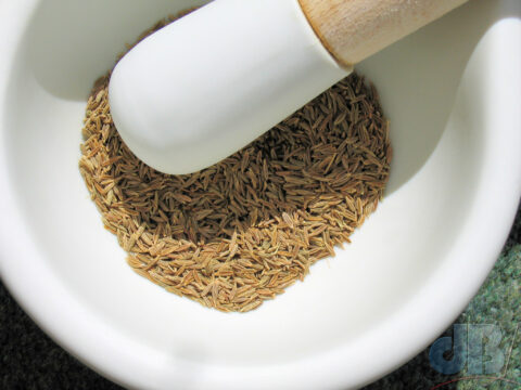Grinding cumin seeds with a pestle and mortar